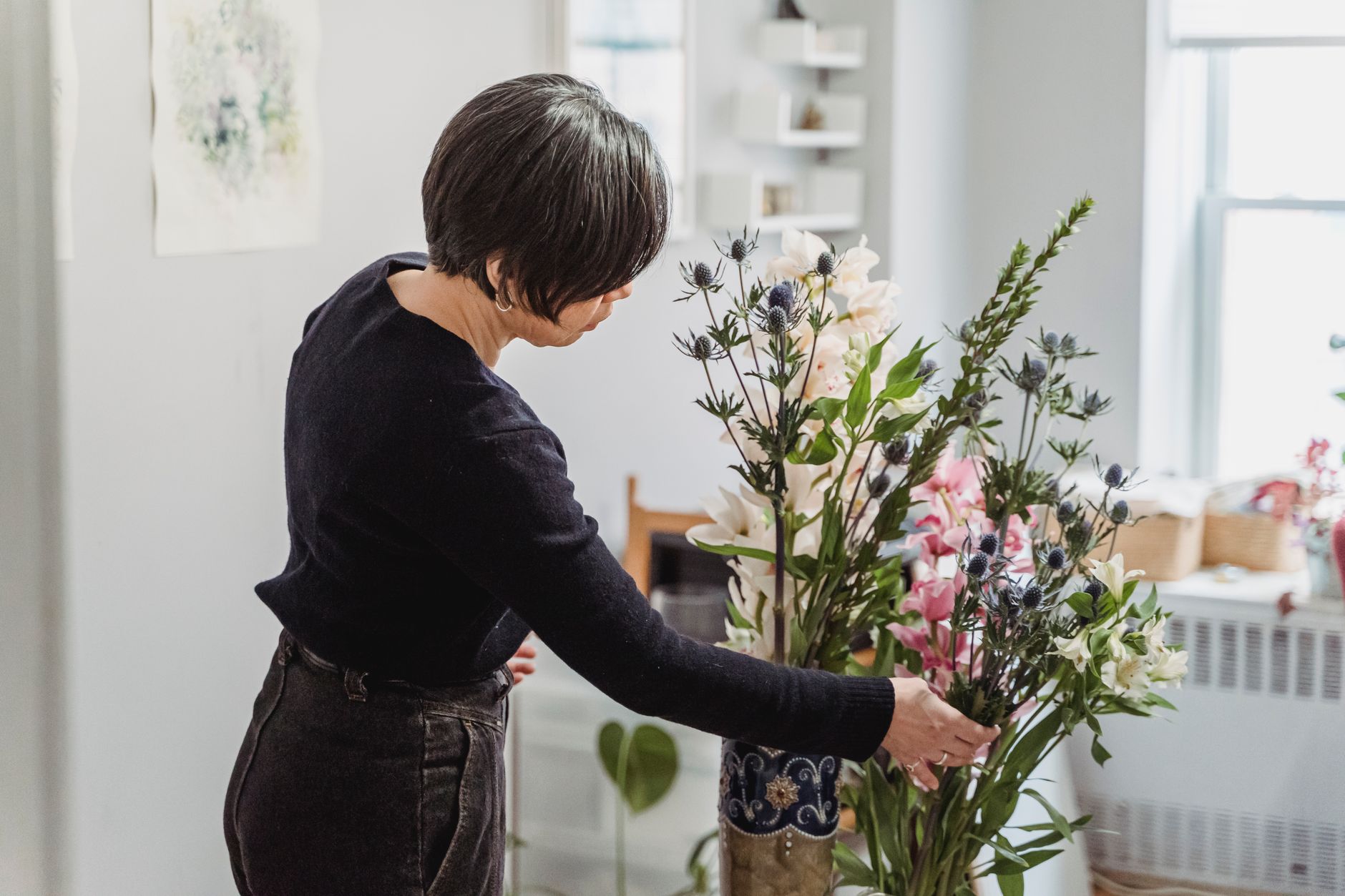 A woman carefully arranges a vibrant floral display in a well-lit home setting. — Beste Wedden Sites Promotiecode Wedden