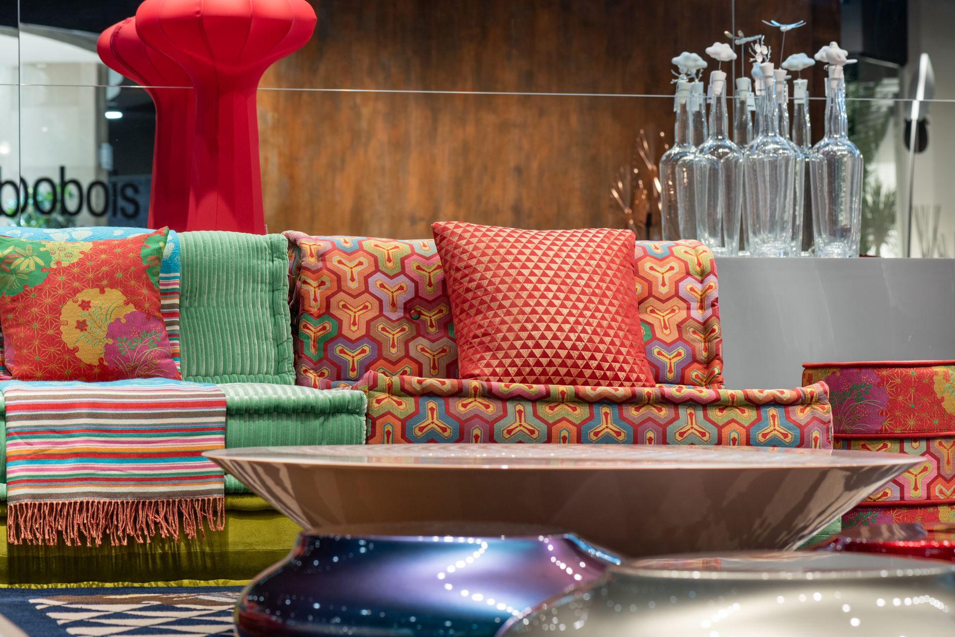 Multicolored comfortable sofa with bright cushions and vivid textile placed near modern round table in contemporary furniture